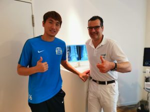 Fußballspieler Rui steht Li mit Dr. Simon im Behandlungsraum